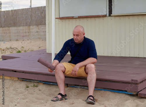 man on a painted porch with a roller in his hand photo