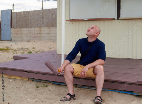 man on a painted porch with a roller in his hand photo