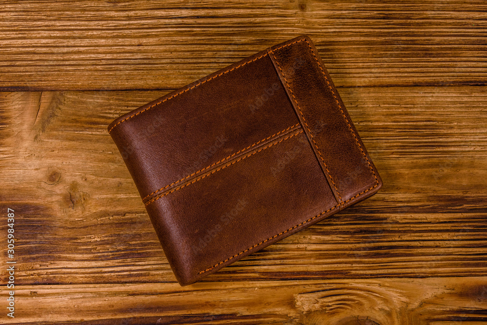 Closed brown leather wallet on wooden table. Top view Closed brown leather wallet on wooden table. Top view