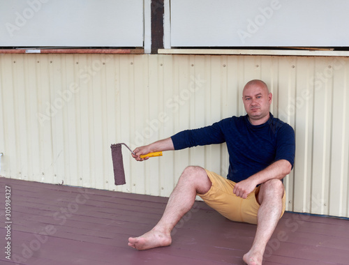 man on a painted porch with a roller in his hand photo