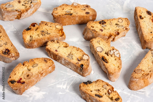 Tasty traditional Italian homemade biscotti or cantuccini cookies with hazelnuts  almonds and walnuts on a light gray background.