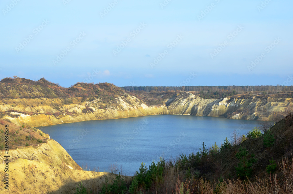 Artificial lake was is formed after the extraction of chalk in an industrial quarry at Krasnoselsky village in the Belarus. Water in open pit between the mountains. Belarusian Maldives