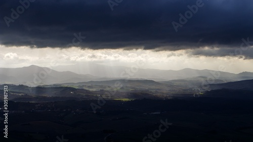 landsape in tuscany or toscana in italy in the mountains with hills and valleys under dramatic cloudy sky illuminated with sunrays