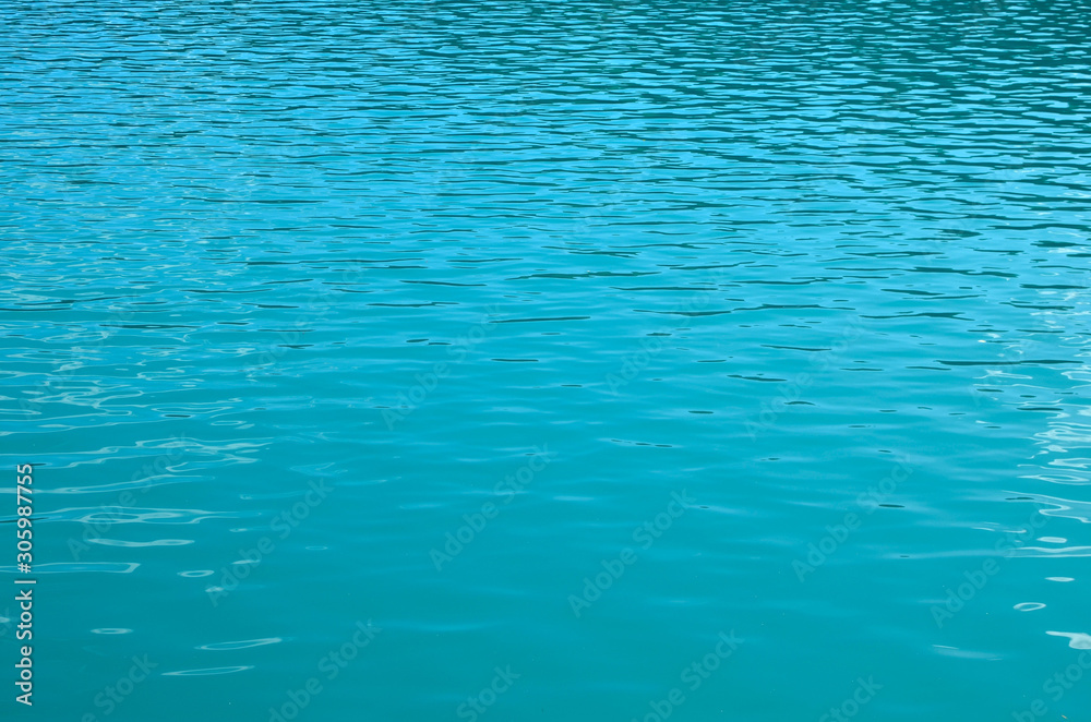 Obraz premium Turquoise clear ocean water background in summer tropical season. Transparent sea water texture with sunny reflections. Travel in paradise
