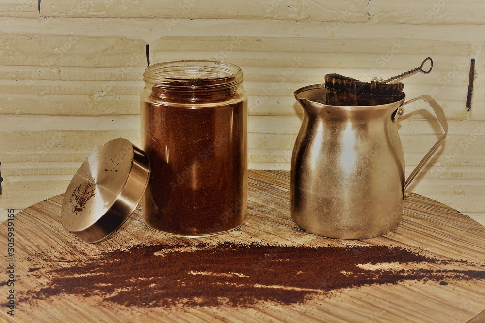 Jarra y envase de cafe con un colador y cafe regado en la mesa Stock Photo