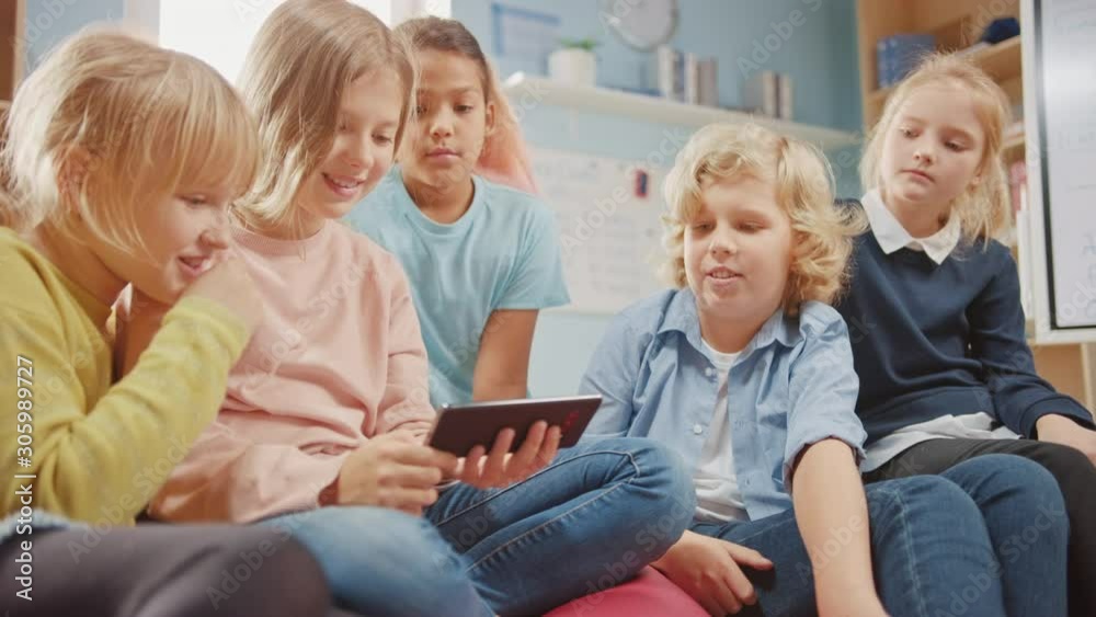 Diverse Group of Cute Small Children Sitting together on the Bean Bags Use Smartphone and Talk, Have Fun. Kids Browsing on Internet and Playing Online Video Games on Mobile Phone Diverse Group of Cute Small Children Sitting together on the Bean Bags Use Smartphone and Talk, Have Fun. Kids Browsing on Internet and Playing Online Video Games on Mobile Phone