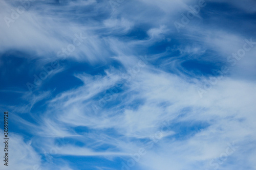 An abstract of swirling wispy clouds in a deep blue sky. 