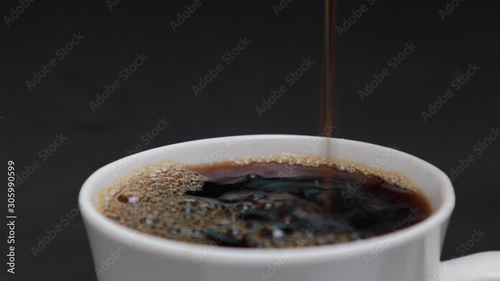 pouring steaming hot black coffee with smoke in to a white cup with beverage drink coffee, black background	