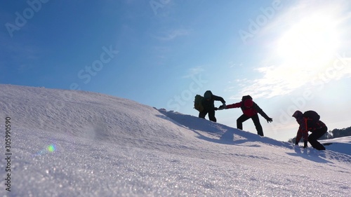 climbers holding hands helping each other climb snowy hill. well-coordinated teamwork in winter tourism. team of travelers in winter go to their goal of overcoming difficulties.