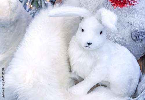 Soft toy of a white rabbit on white fur. © Valemaxxx