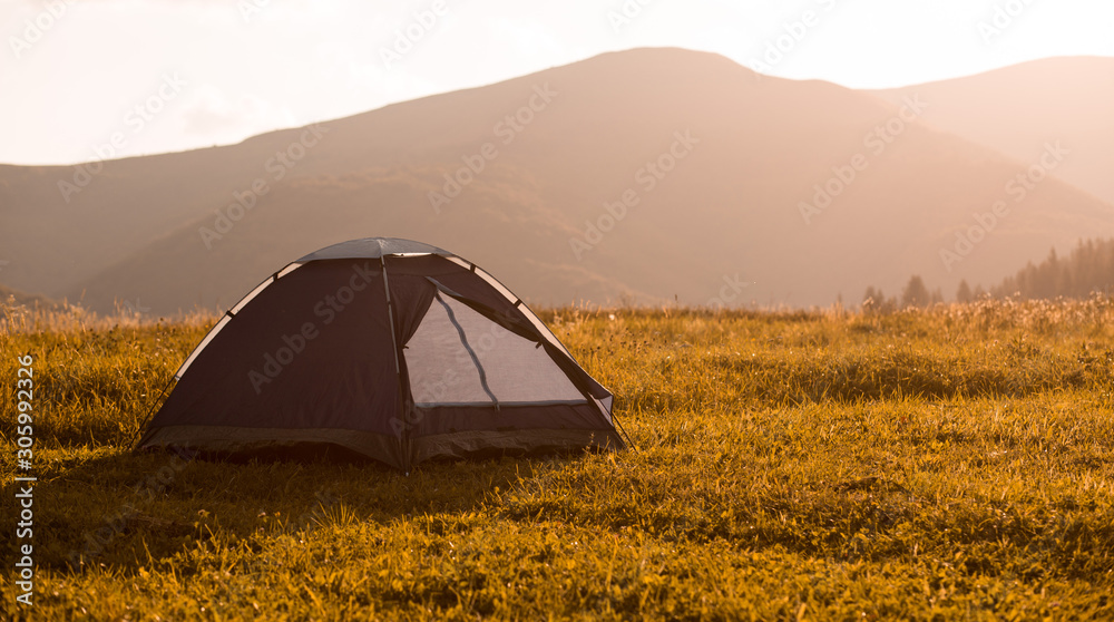 Blue tent with autumn sunset in mountains landscape