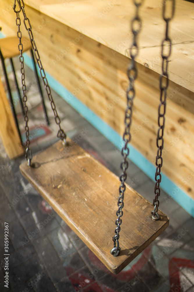 Wooden swing on a chain in a summer cafe. Wooden swing on a chain in a summer cafe.