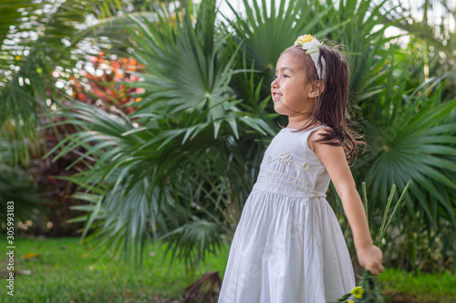 A girl in the garden with headband  white dress  very happy in profile