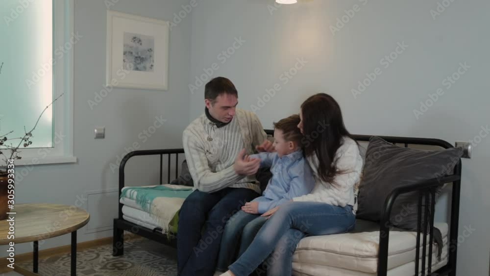 Beautiful and happy dad mom and son on the couch in a modern interior. Beautiful and happy dad mom and son on the couch in a modern interior.