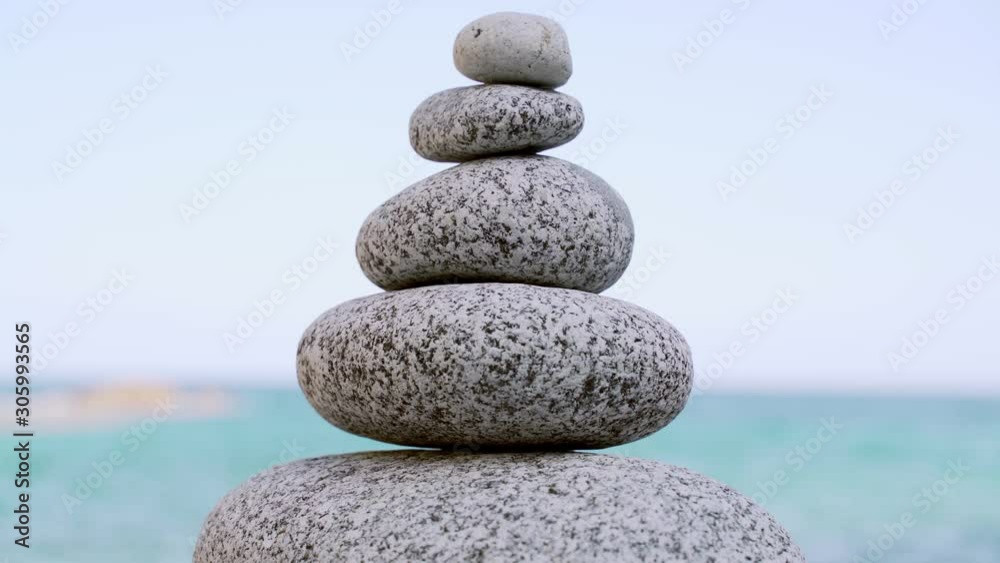 Stone tower on the beach against the azure sea. Beautiful rocks on the background. Peace and tranquility. Clean blue sky. Soul balance. Cobblestone sculptures. Stone tower on the beach against the azure sea. Beautiful rocks on the background. Peace and tranquility. Clean blue sky. Soul balance. Cobblestone sculptures.