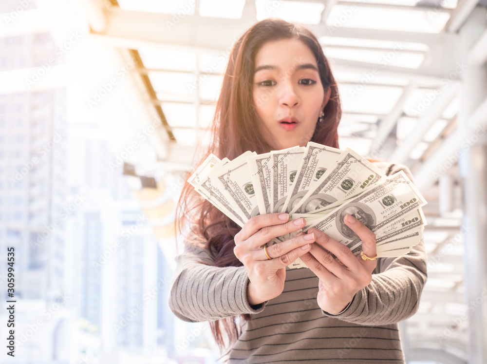Happy woman holding banknotes and the city background. woman with money, windfall rich or fortune Happy woman holding banknotes and the city background. woman with money, windfall rich or fortune
