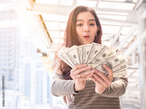 Happy woman holding banknotes and the city background. woman with money, windfall rich or fortune