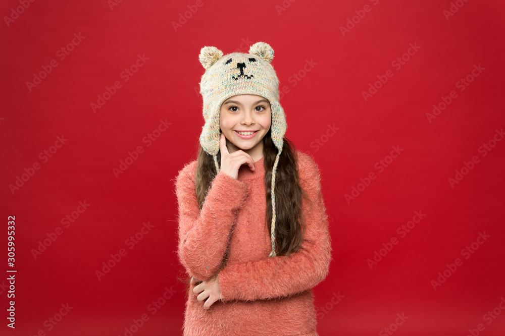 Adorable small bear. Winter outfit. Little kid wear knitted hat. Stay warm. Little girl winter fashion accessory. Small child long hair wear hat red background. Cute model enjoy winter style Adorable small bear. Winter outfit. Little kid wear knitted hat. Stay warm. Little girl winter fashion accessory. Small child long hair wear hat red background. Cute model enjoy winter style