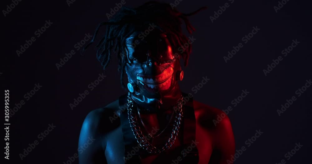 Shirtless man with monster face mask in ultraviolet light