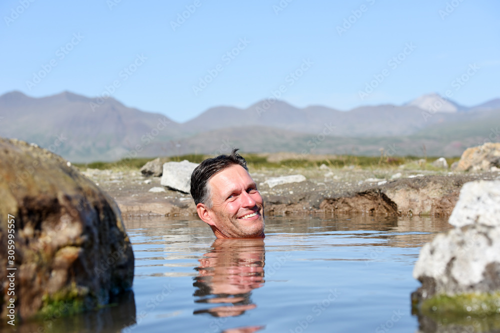Fototapeta premium Man bathing and relaxing in hot springs during summer day. Natural hot geothermal springs and pool in the Iceland, Europe.
