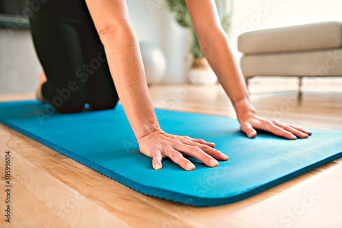 Close mat woman enjoying yoga indoors in the living room © Louis-Photo