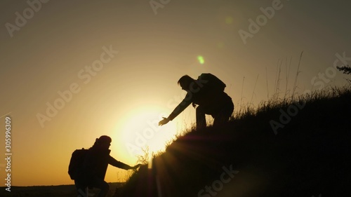 teamwork of business people. traveler man extends his hand to a girl climbing to the top of hill. travelers climb the cliff holding hand. Happy family on vacation. tourists hug on top of mountain