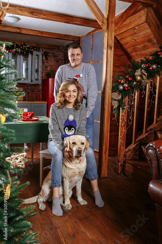 family on the floor against the background of a Christmas tree with a dog © Andrii