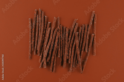 Dog food pattern made with dry snacks sticks. Flat lay texture in brown earthy tones. Home pets  animals feeding. Special diet  training supply.