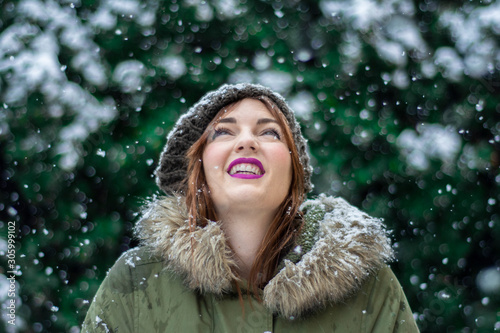 chica joven en primer plano en un fondo verde mientras nieva