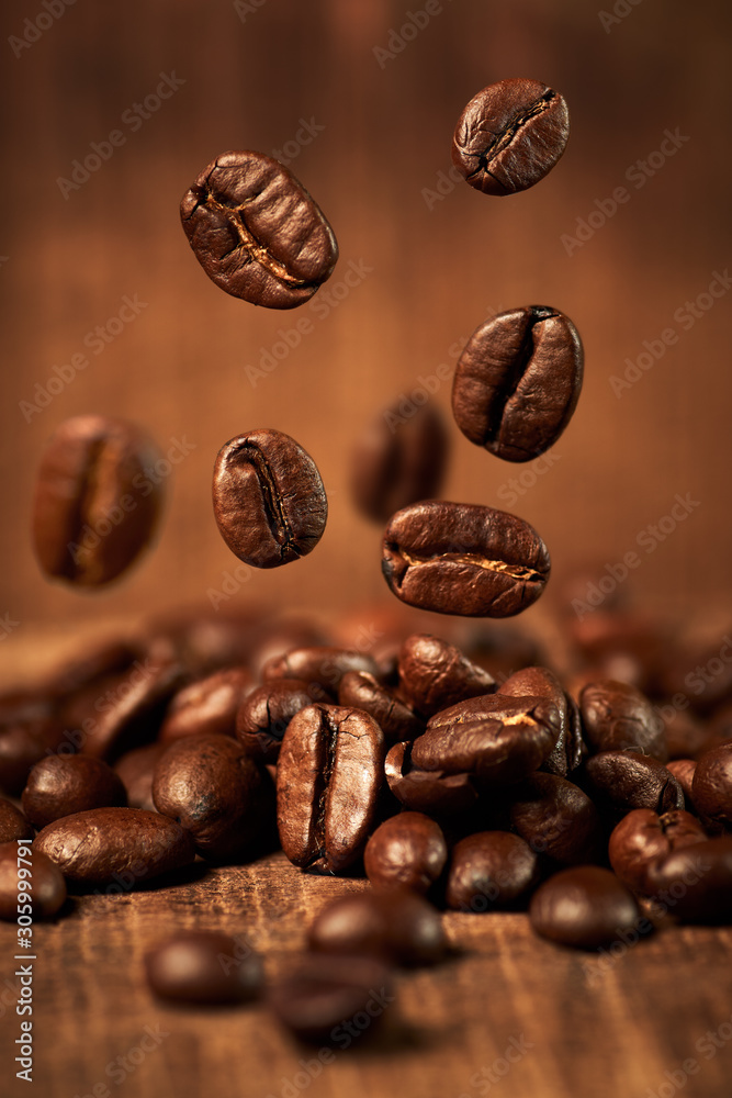Fototapeta premium Kaffeebohnen fliegen auf Holztisch