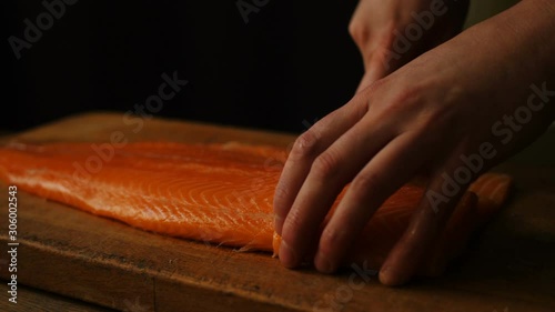 A chef cuts a smoked salmon filet with a knife on a table