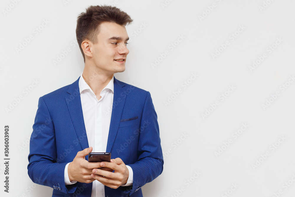 Young business man using his mobile device in business. Modern young guy with a phone in hand. Social networks business. Handsome man work on phone. Happy handsome guy browsing with his mobile device. Young business man using his mobile device in business. Modern young guy with a phone in hand. Social networks business. Handsome man work on phone. Happy handsome guy browsing with his mobile device.