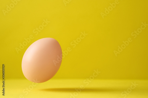 Chicken Egg Falling On Ground Against Yellow Background