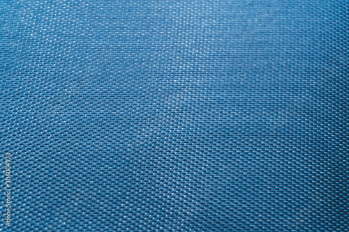 Close-up of abstract flat blue high detail textured clothing fabric pattern background in partial focus and realistic light reflections