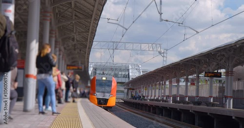 The platform of the ground station of the metro is full of passengers and the train is just arriving