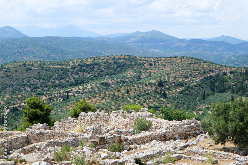 Ruins of ancient greek city Mycenae acropolis with hills coverd by olive trees on the background