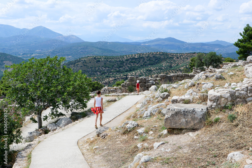 tourist family mother and son walking on the ruins of famous ancient greek city Mycenae in the summer