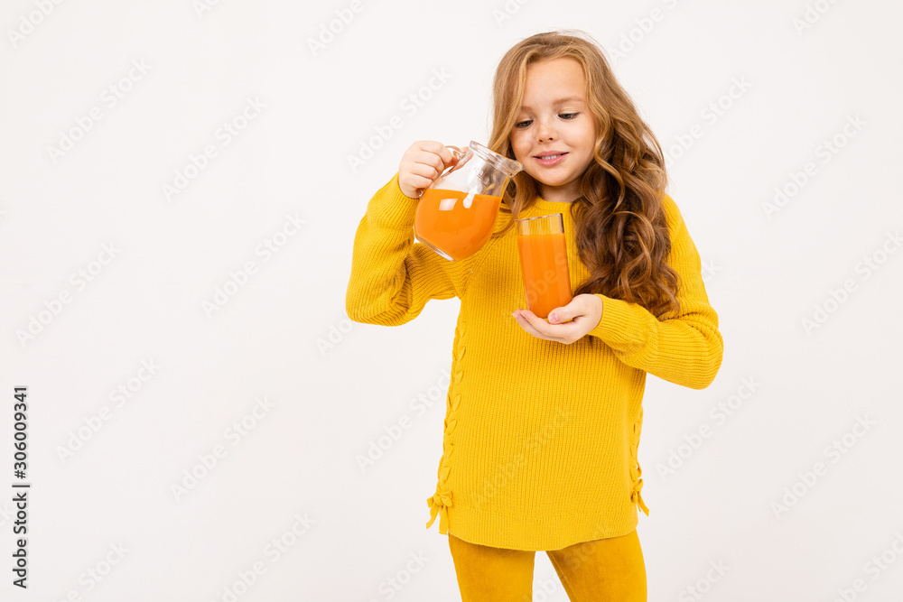 young girl pours carrot juice from a jug into a glass on a white background young girl pours carrot juice from a jug into a glass on a white background