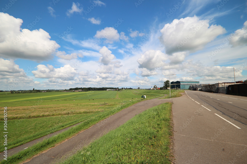 Dutch landscape with industries along the dike of river Hollandsche IJssel, meadows in the low Zuidplaspolder