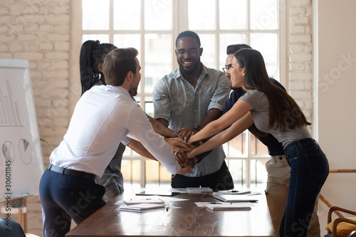 Фотография Overjoyed happy multiethnic young teammates celebrating employees unity at office