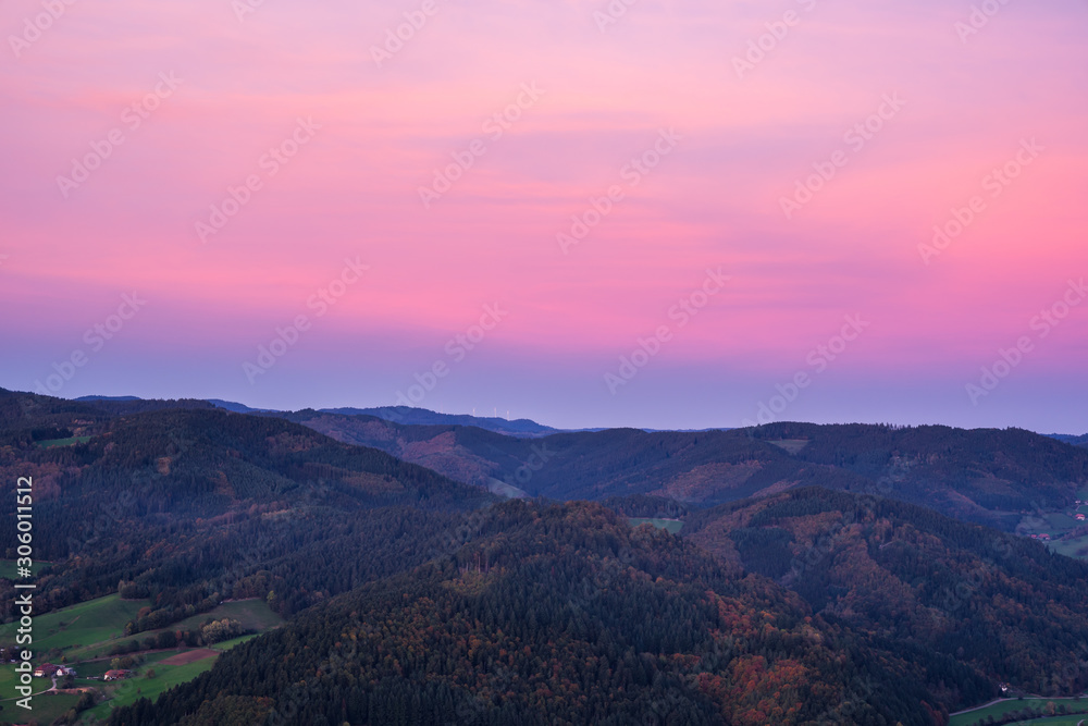 Germany, Red afterglow sky after sunset, aerial view above tree covered, forested mountains of black forest nature landscape in autumn