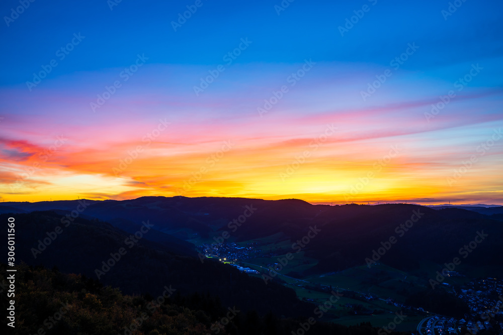 Germany, Colorful sunset sky decorating black forest hills and mountains nature landscape surrounding houses of a village, aerial view above