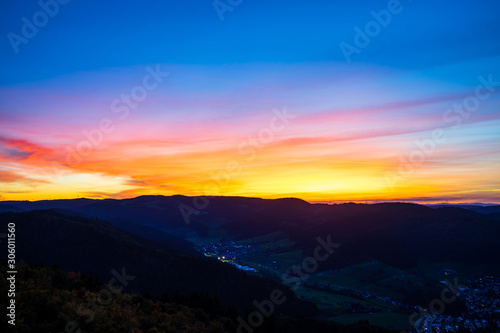 Germany, Colorful sunset sky decorating black forest hills and mountains nature landscape surrounding houses of a village, aerial view above © Simon