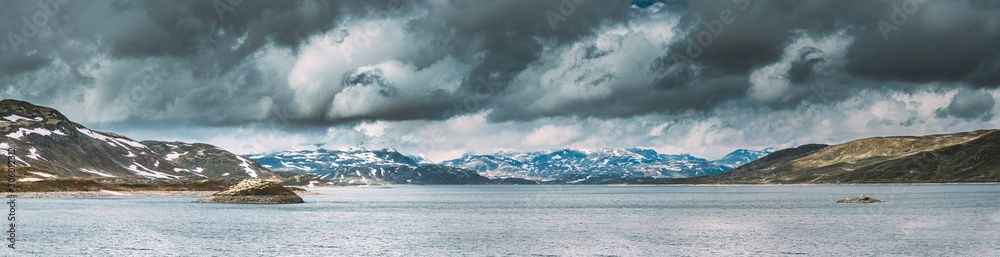 Oppland, Tyin Lake, Norway. Stones On Coast Of Beautiful Lake Tyin In Summer Cloudy Day. Norwegian Nature. panorama, panoramic view.