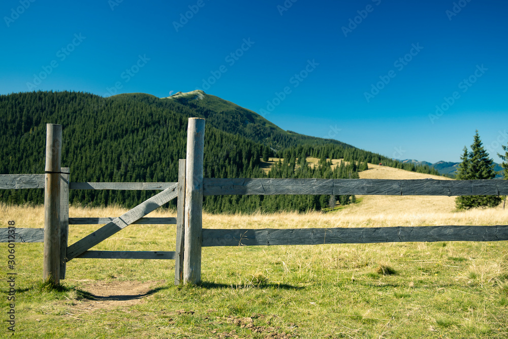 highland mountain wilderness scenic environment and rural wooden fence with small gate of paddock area for horses in village space far from civilization 