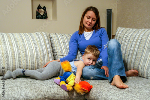 2011.01.02, Maloyaroslavets, Russia. A little boy holds a toy and lying on sofa by his mother. Happy family resting at home.  photo