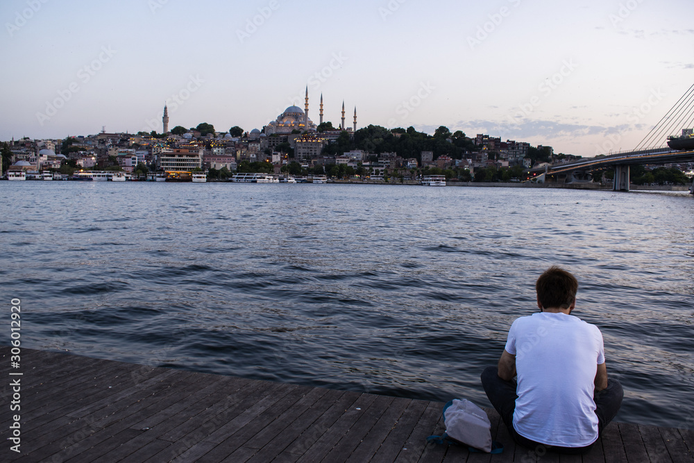 Fototapeta premium Istanbul: people from behind chasing sunset with view of the skyline of the city and the Suleymaniye mosque, Ottoman imperial mosque ordered by Suleiman the Magnificent and designed by Mimar Sinan