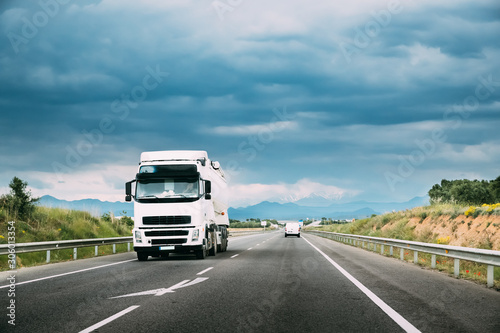 White Truck Or Traction Unit In Motion On Road, Freeway. Asphalt Motorway Highway Against Background Of Mountains Landscape. Business Transportation, Trucking Industry © Grigory Bruev