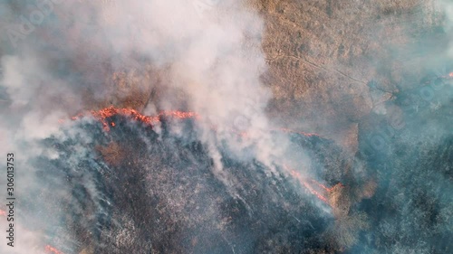 Strong fire in an empty field. Strong smoke from the burning place. View from a height, vertically from top to bottom, smooth rise up.