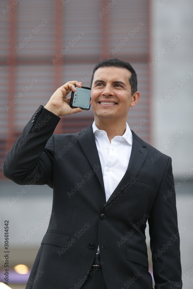 Handsome Latino executive man leaving office, talking on the phone and wearing casimir suit Handsome Latino executive man leaving office, talking on the phone and wearing casimir suit